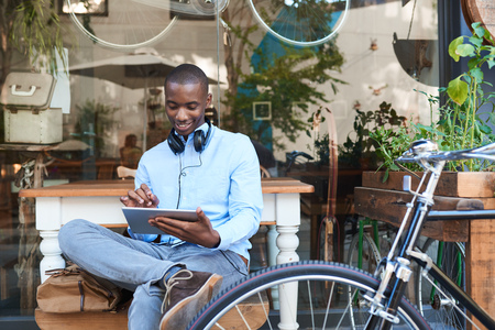 Young man browsing the internet at a sidewalk cafeの写真素材