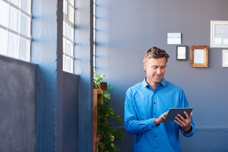 Businessman standing in an office using a digital tabletの写真素材