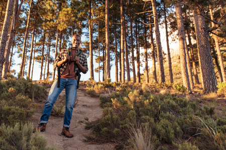 Smiling African man standing on a trail in the forestの写真素材
