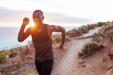 Fit young man running alone along an oceanside trailの写真素材