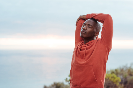 Young African man stretching before a run along the oceanの写真素材