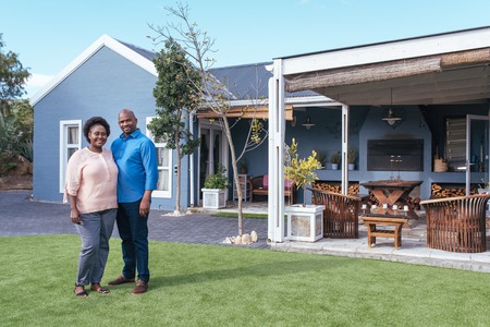 Smiling African couple standing outside on their lawnの写真素材