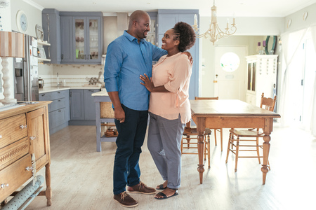Affectionate African couple smiliing and standing together in their kitchenの写真素材