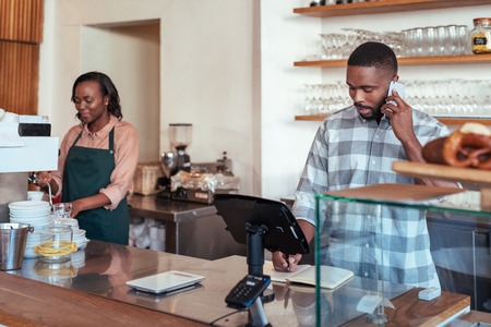 Young African entrepreneurs working together behind their cafe counterの写真素材