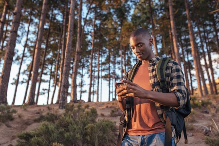 Young African man using gps while hiking in a forest