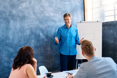 Mature businessman giving a presentation to coworkers in an officeの写真素材