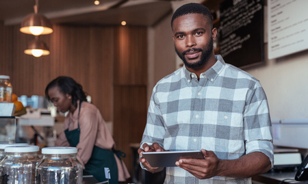 Young African entrepreneur working at the counter of his cafeの写真素材