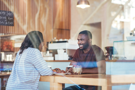 Young African couple talking together over coffee in a cafeの写真素材