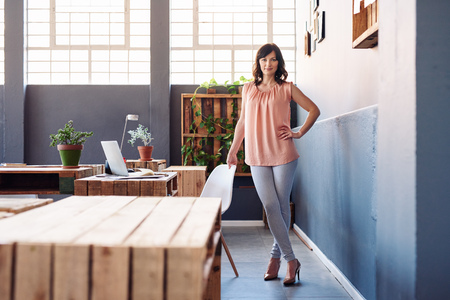 Confident young businesswoman standing alone in a modern officeの写真素材