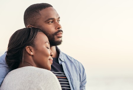 Young African couple enjoying a sunset at the beachの写真素材