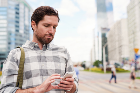 Young man standing in the city using a cellphoneの写真素材