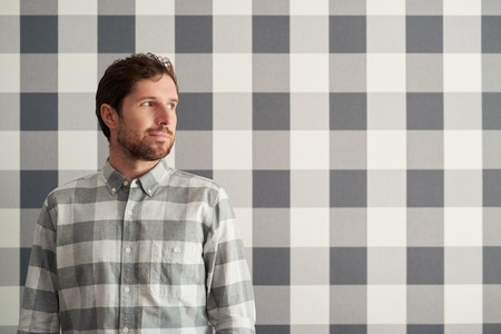 Young man wearing a checkered shirt matching his wallpaperの写真素材