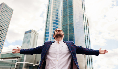 Businessman with arms raised skyward standing in the cityの写真素材
