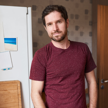 Handsome man standing in his modern kitchen in the morningの写真素材