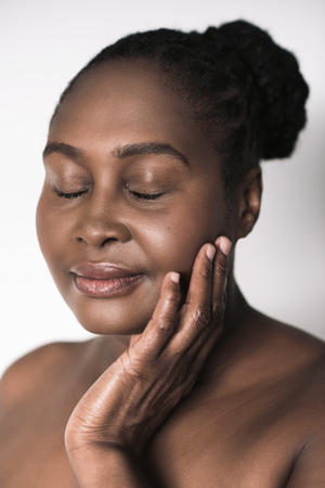 African woman with her eyes closed touching her cheekの写真素材