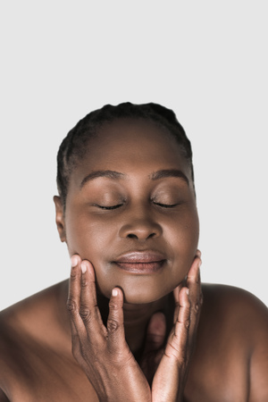 Beautiful African woman touching her face against a white backgroundの写真素材