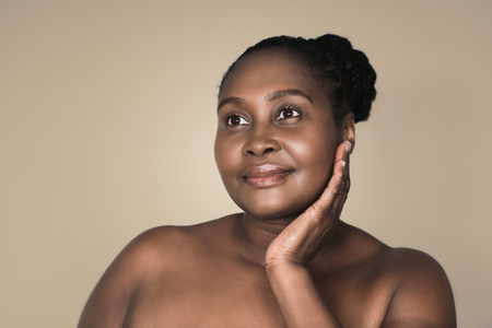 Young African woman smiling and touching her cheekの写真素材