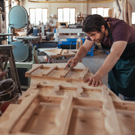 Craftsman skillfully sanding wood while working in his carpentry studioの写真素材