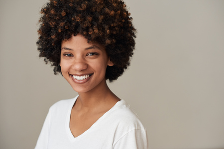 Smiling young African woman standing against a gray backgroundの写真素材