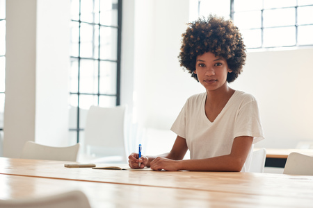 Confident young African female student studying at a campus tableの写真素材