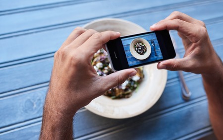 Man talking pictures of his salad at a bistro tableの写真素材