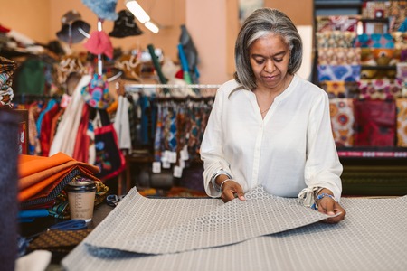 Mature woman looking at cloth in her fabric shopの写真素材
