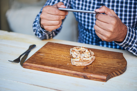 Man talking pictures of his sandwich at a bistro tableの写真素材
