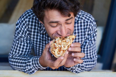 Man biting into an open face sandwich in a bistroの写真素材