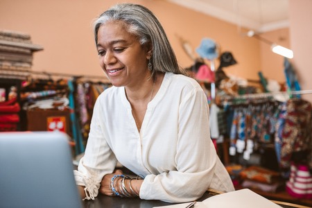 Smiling mature woman working online in her fabric storeの写真素材