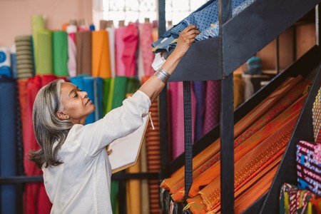 Mature woman checking inventory in her fabric shopの写真素材