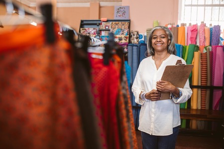 Smiling woman standing with a clipboard in her fabric shopの写真素材