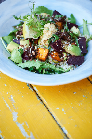 Healthy mixed salad sitting on a rustic yellow wooden tableの写真素材