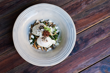 Delicious bowl of poached eggs on mushrooms, feta and greensの写真素材