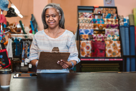 Smiling woman working at a counter in her fabric shopの写真素材