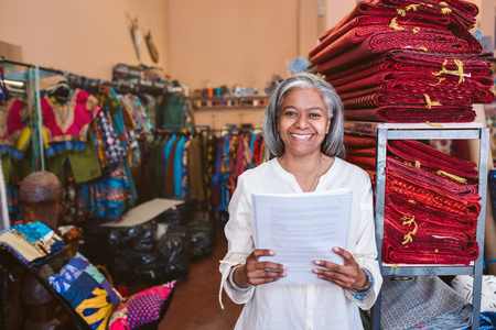 Smiling mature woman standing in her fabric shop reading paperworkの写真素材