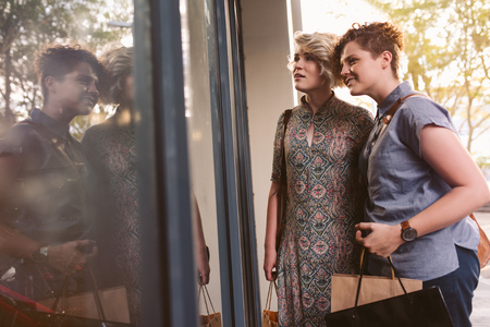 Smiling lesbian couple window shopping together in the city