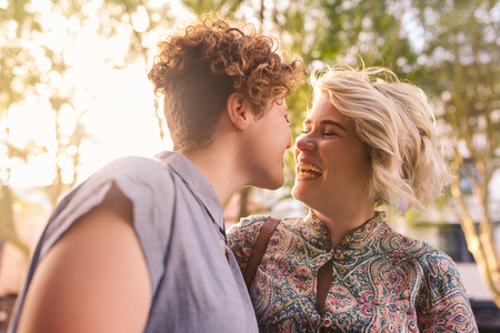 Young lesbian couple laughing together other on a sunny streetの写真素材