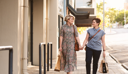Young lesbian couple walking with shopping bags in the cityの写真素材