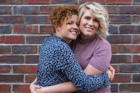 Young woman giving her smiling girlfriend an affectionate kissの写真素材