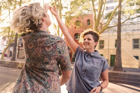Smiling  couple holding hands and dancing in the city