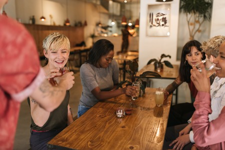 Group of smiling female friends ordering drinks in a bistro
