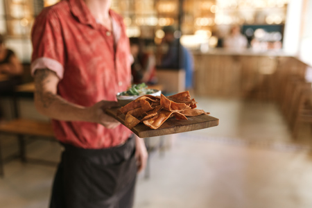 Waiter serving up a board of freshly baked nachosの写真素材