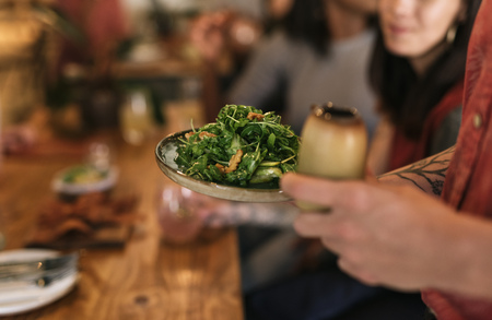 Waiter serving a healthy salad to bistro customersの写真素材