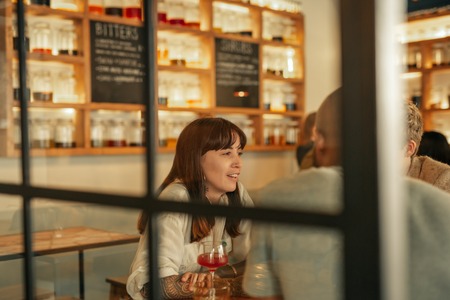 Young woman talking with friends over drinks in a barの写真素材