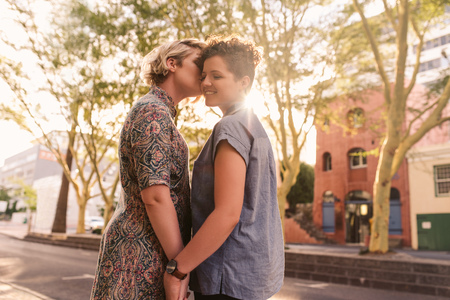 Affectionate young lesbian couple standing together on a city streetの写真素材