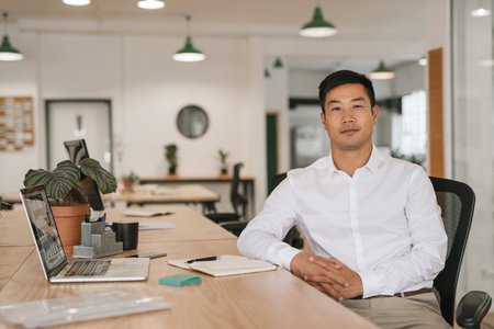 Confident Asian businessman working at his office deskの写真素材
