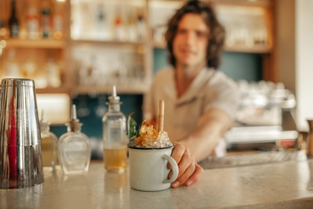 Bartender serving drinks behind the counter of a trendy barの写真素材