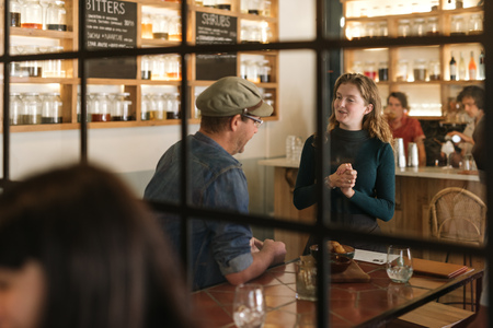 Smiling young waitress talking with a bistro customerの写真素材