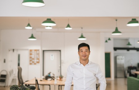 Young Asian businessman smiling confidently while standing in an officeの写真素材