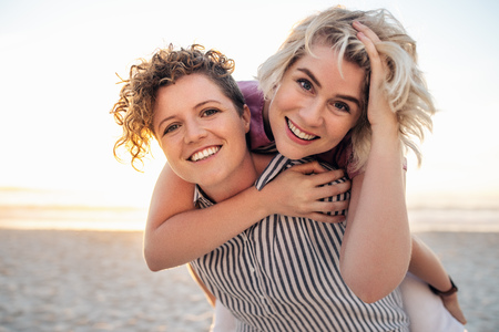 Laughing young lesbian couple having fun together at the beachの写真素材